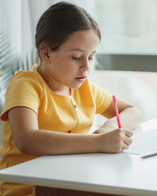 A girl concentrating as she writes at a table